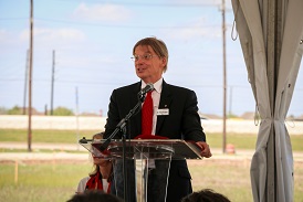 A sandy blond man with glasses speaking at an podium