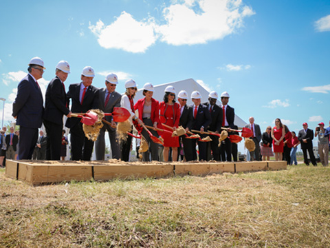 Group of people in suits shoveling dirt