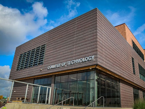 Sign that says "College of Technology" on the exterior of a brown brick building.