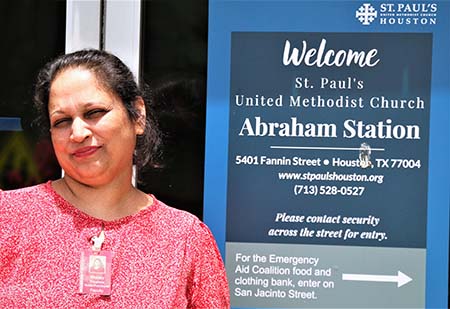 Portait picture of an Indian woman standing in front of a clinic sign.