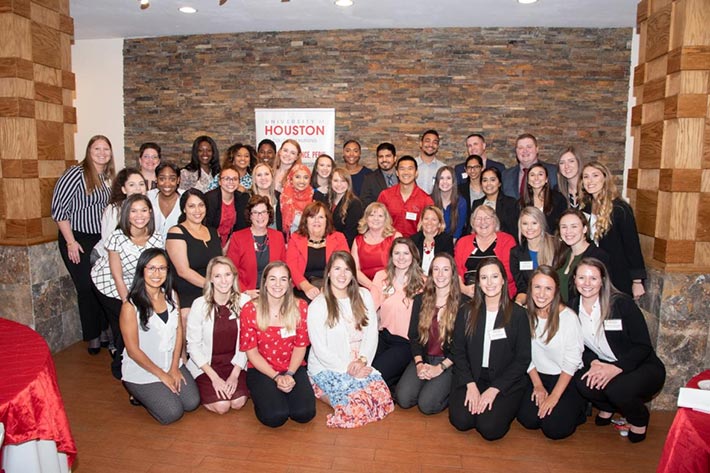 A group of nursing students and faculty together in a banquet hall.