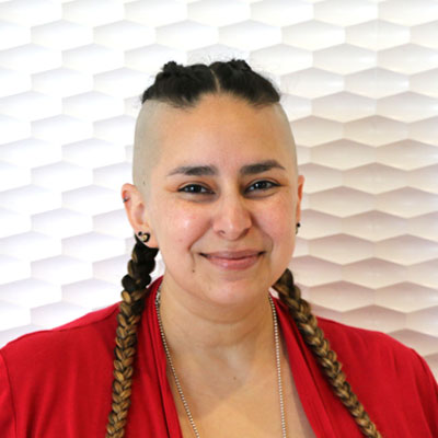 Portrait of a Hispanic woman smiling with dark hair in pigtails wearing a red jacket