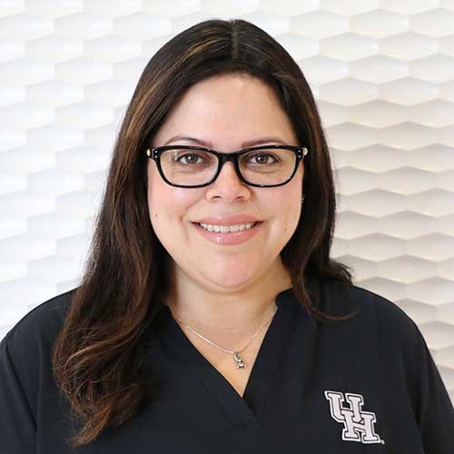 Portrait of a Hispanic woman smiling with glasses and dark shoulder length hair wearing a black tunic