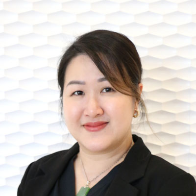 Portrait of a Asian woman smiling with black hair tied up wearing a black top